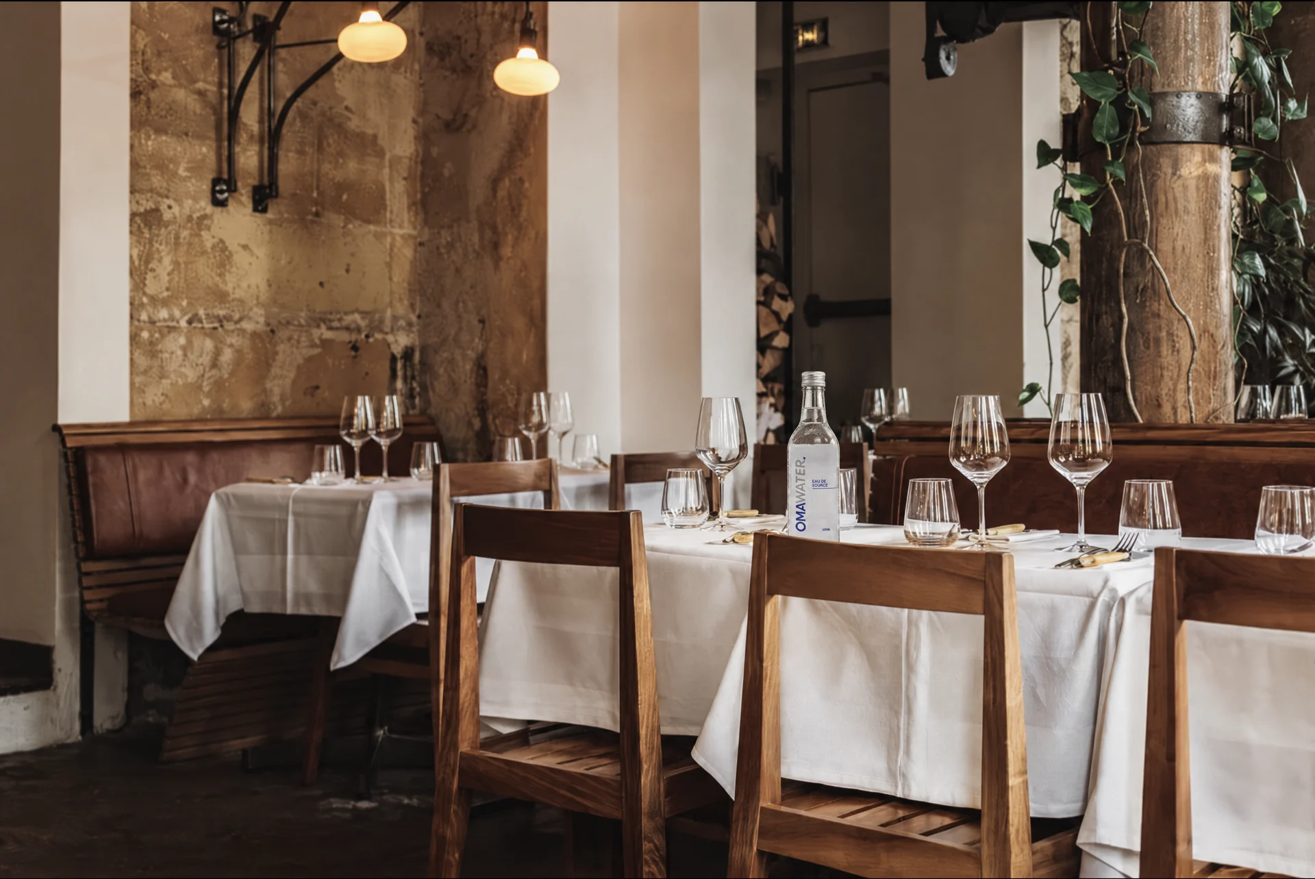 Salle de restaurant dressée avec bouteilles d'eau OMA Water